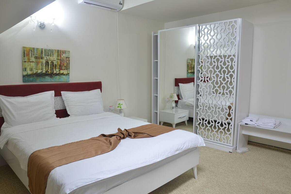 Un dormitorio con cama, armario, mesita de noche y lámpara.