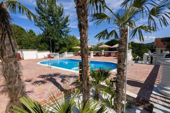 A swimming pool surrounded by palm trees and a patio area with outdoor seating. - Virginia Gardens  (Baile Govora)