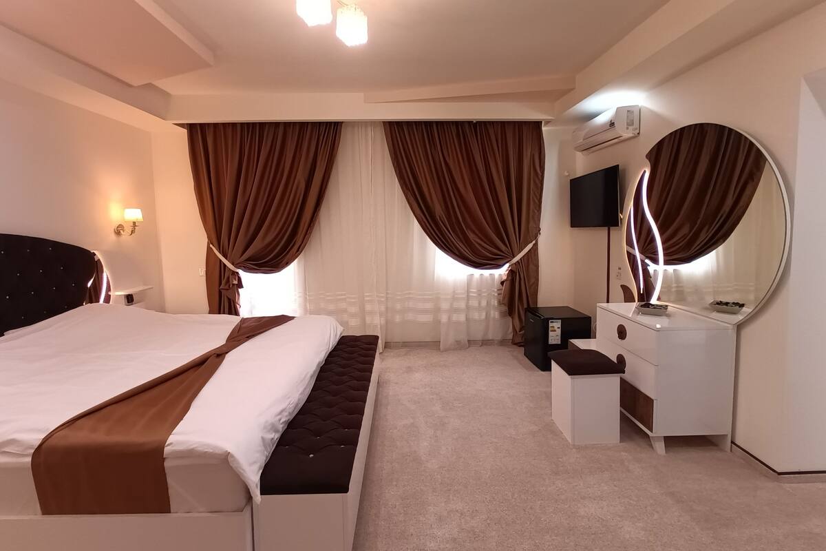 Una habitación de hotel con una cama, un tocador, un espejo y un televisor.