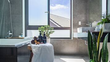 A modern bathroom with a large window, a shower, and a vanity with a mirror.