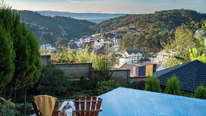 A pool with a wooden deck, a chair, and a view of a hillside town.
