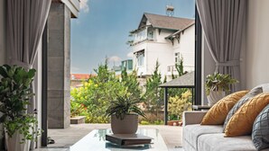 A living room with a sofa, a coffee table, and a potted plant. - Zenora Hillside Garden (Xuan Huong - Da Lat)