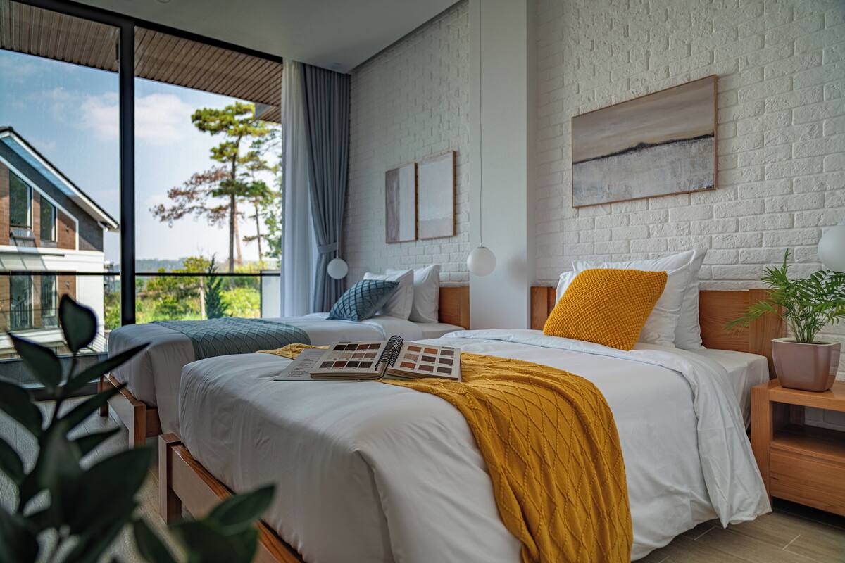 Un dormitorio moderno con dos camas, un ventanal grande y vistas al exterior.