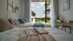 A bedroom with a large bed, a desk, and a view of the outdoors.