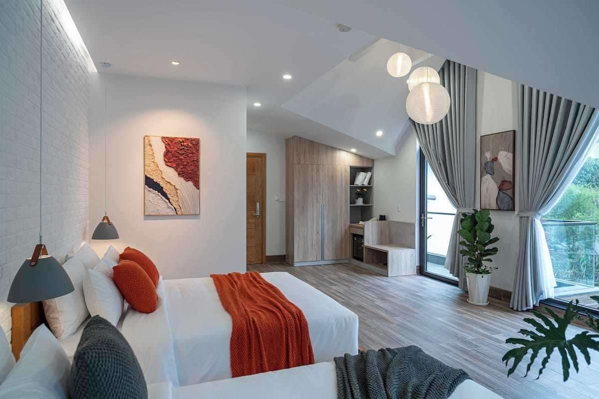 Una habitación de hotel moderna con una cama grande, un área de comedor y vistas al exterior.
