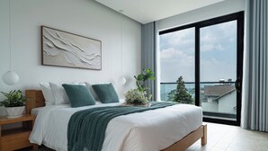 A modern bedroom with a large bed, a view of the city, and a balcony.