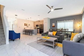 A modern living room with a sofa, coffee table, and a dining area with a table and chairs. - SL2964PS - Luxurious 5Bdrooms Villa with Priv Pool (Kissimmee)