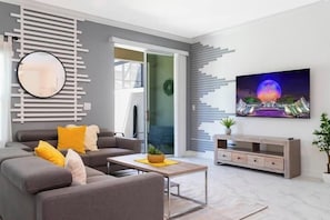 A modern living room with a grey sofa, yellow cushions, a coffee table, a TV, and a decorative wall panel. - SL2964PS - Luxurious 5Bdrooms Villa with Priv Pool (Kissimmee)