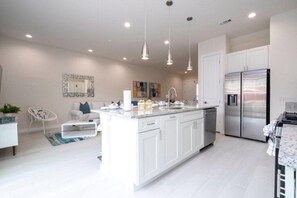 A modern kitchen with white cabinetry, stainless steel appliances, pendant lighting, and a central island. - SR7512SC - Sunny Villa Near Disney (Kissimmee)