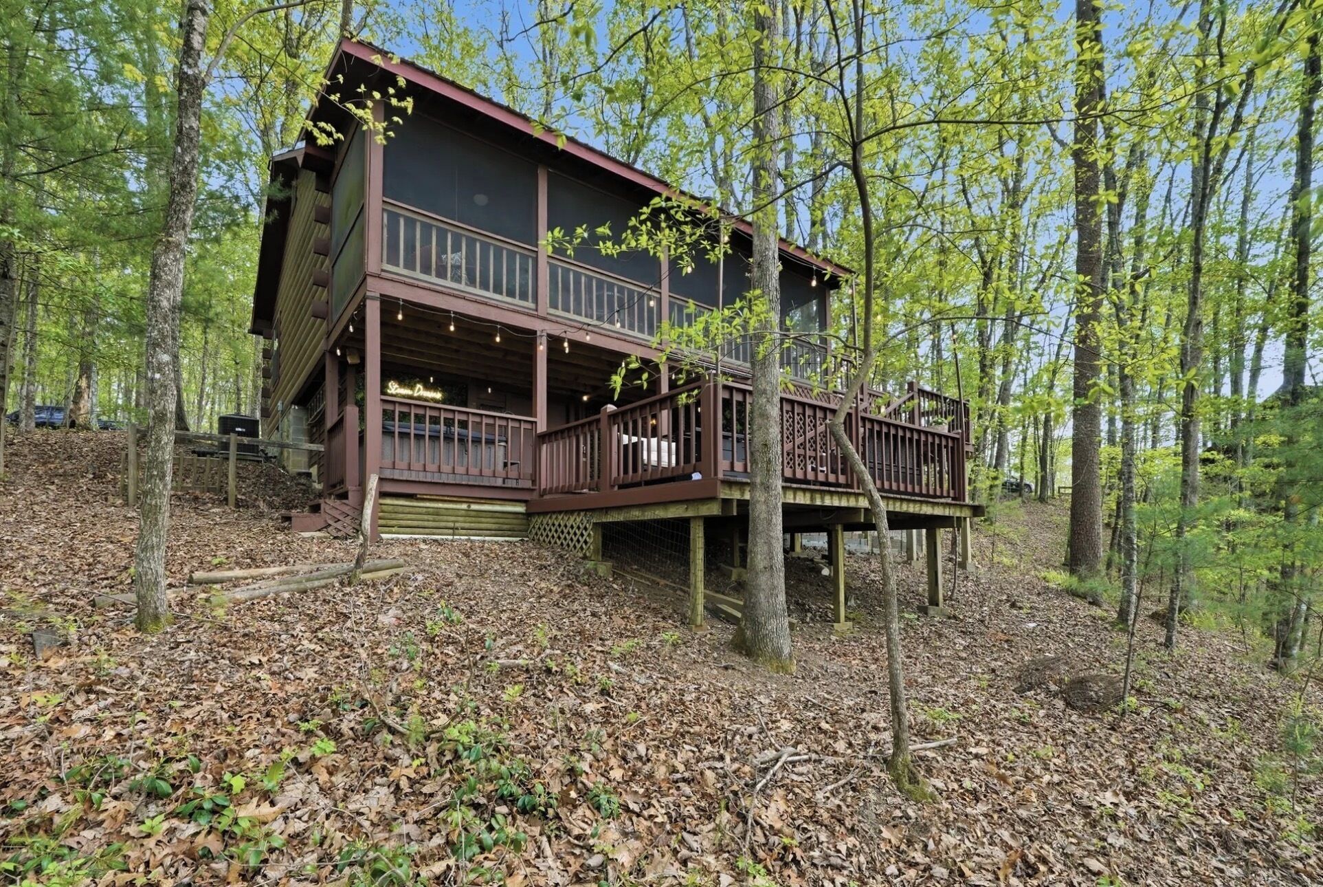 A cabin with a balcony, surrounded by trees.