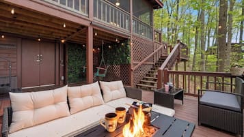 A deck with a sofa, a fire pit, and outdoor furniture.