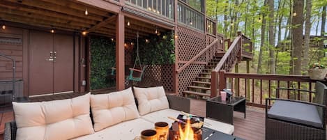 A deck with a sofa, a fire pit, and outdoor furniture.