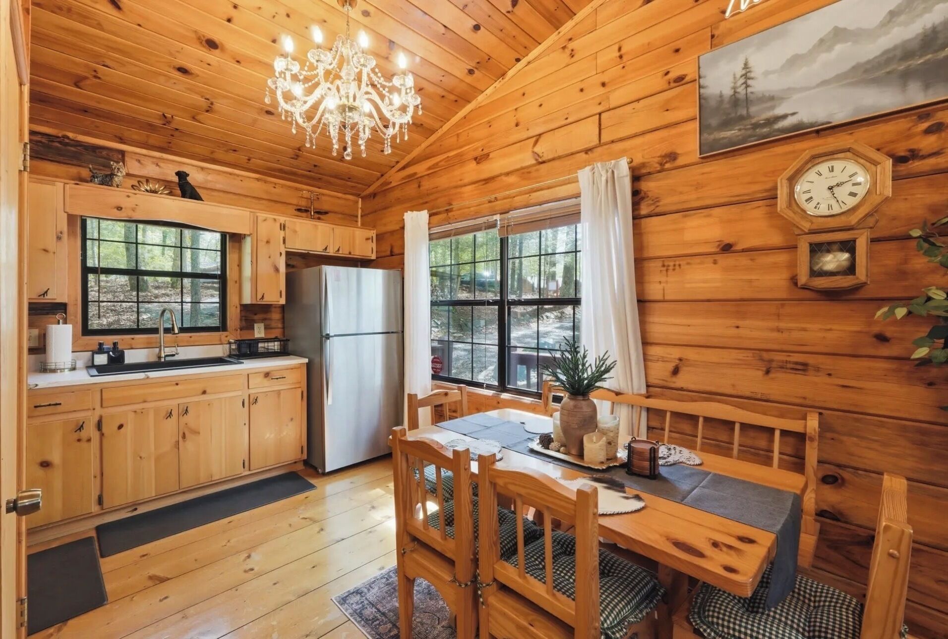 A wooden cabin with a kitchen, dining area, and a large window.