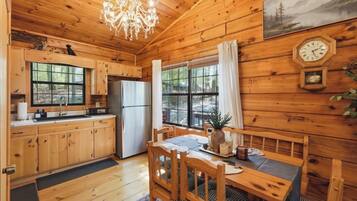 A wooden cabin with a kitchen, dining area, and a large window.