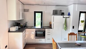 A modern kitchen with white cabinets, a Bosch oven, a microwave, and a refrigerator.