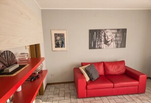 Ein Wohnzimmer mit einem roten Sofa, einem Couchtisch mit Dekoration und zwei gerahmten Kunstwerken an der Wand.