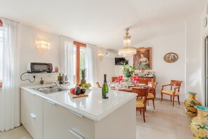 A kitchen with a built-in microwave, a sink, and a dining area with a table and chairs. - Apartment in Lucca Near Historic Center (Lucca)
