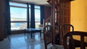 Une pièce avec vue sur la ville, un escalier en bois et un coin repas.
