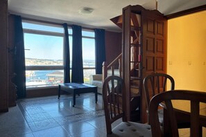 A room with a view of the city, a wooden staircase, and a dining area. - Desconectaengalicia El Pescador 2 (Portonovo)