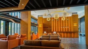 A spacious lobby with leather sofas, a reception desk, and modern chandeliers. - Rooftop Pool Condo Walk to Beach, Gym, Wi-Fi c118 (Tambo kamala)