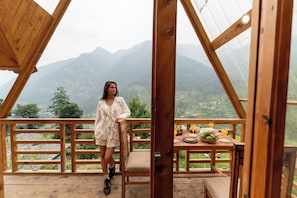 A wooden deck with a table set for breakfast, overlooking a mountainous landscape. - Hillside a frame cottage Jibhi (Jibhi)