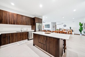 A modern kitchen with wooden cabinets, a central island, and a dining area with wooden furniture. - Beautiful, spacious 4-bedroom Penthouse, where luxury meets comfort. (Jaco)