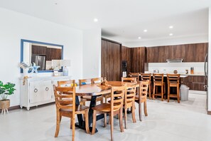 A modern kitchen with wooden cabinets, a dining table with chairs, and a white countertop. - Beautiful, spacious 4-bedroom Penthouse, where luxury meets comfort. (Jaco)