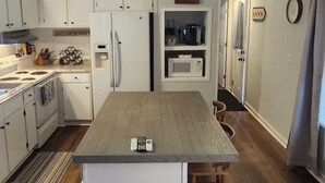 A kitchen with white cabinets, a central island, a microwave, and a refrigerator. - Terrific 2-bedroom mobile home,  perfect for bringing your boat (Wilmington)
