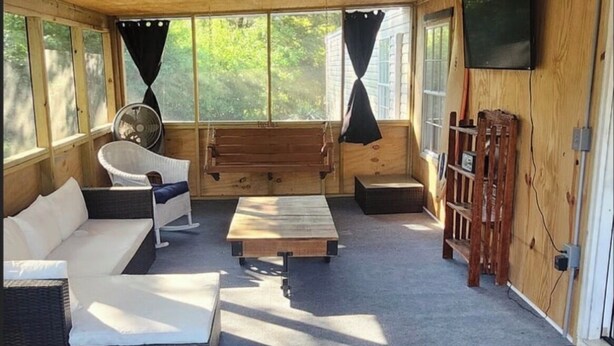 A wooden interior with a sofa, a table, and a TV mounted on the wall. - Terrific 2-bedroom mobile home,  perfect for bringing your boat (Wilmington)