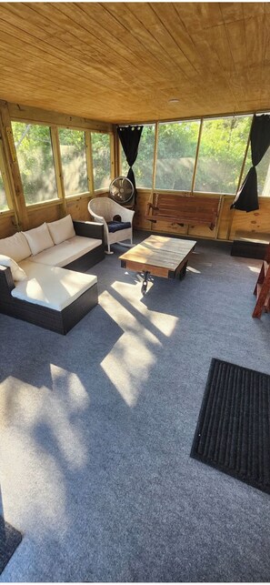 Una habitación acogedora con sofá, una mesita, un ventilador y una hamaca.