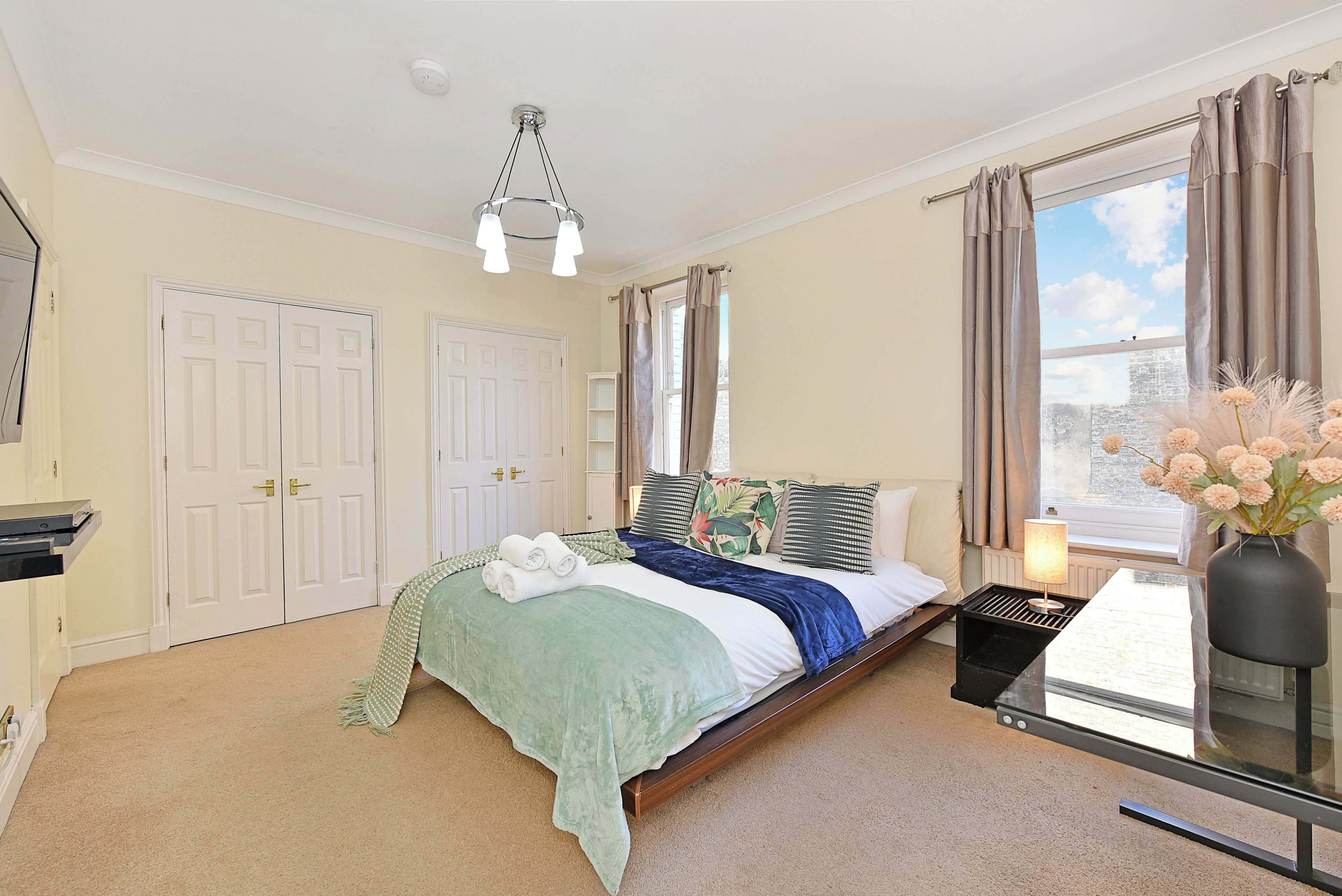 A bedroom with a bed, bedside table, lamp, and window with curtains.