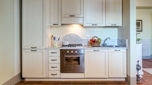 A kitchen with white cabinets, a stove, oven, and a sink. - Apartment in Lucca With Stunning Tuscan Views (Capannori)
