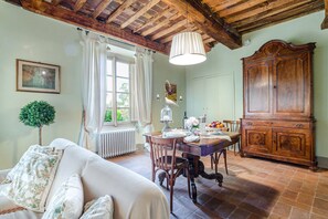 A dining area with a wooden table, chairs, a cabinet, and a radiator. - Apartment in Lucca With Stunning Tuscan Views (Capannori)