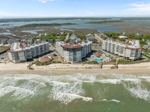 A coastal hotel with multiple buildings, a beach, and a view of the sea. - Shark Tooth Cove: Oceanfront + Pools | Sleeps 8 (North Topsail Beach)