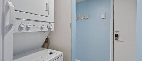 Un área de lavandería con lavadora y secadora de carga frontal, una pared azul y una puerta con cerradura.
