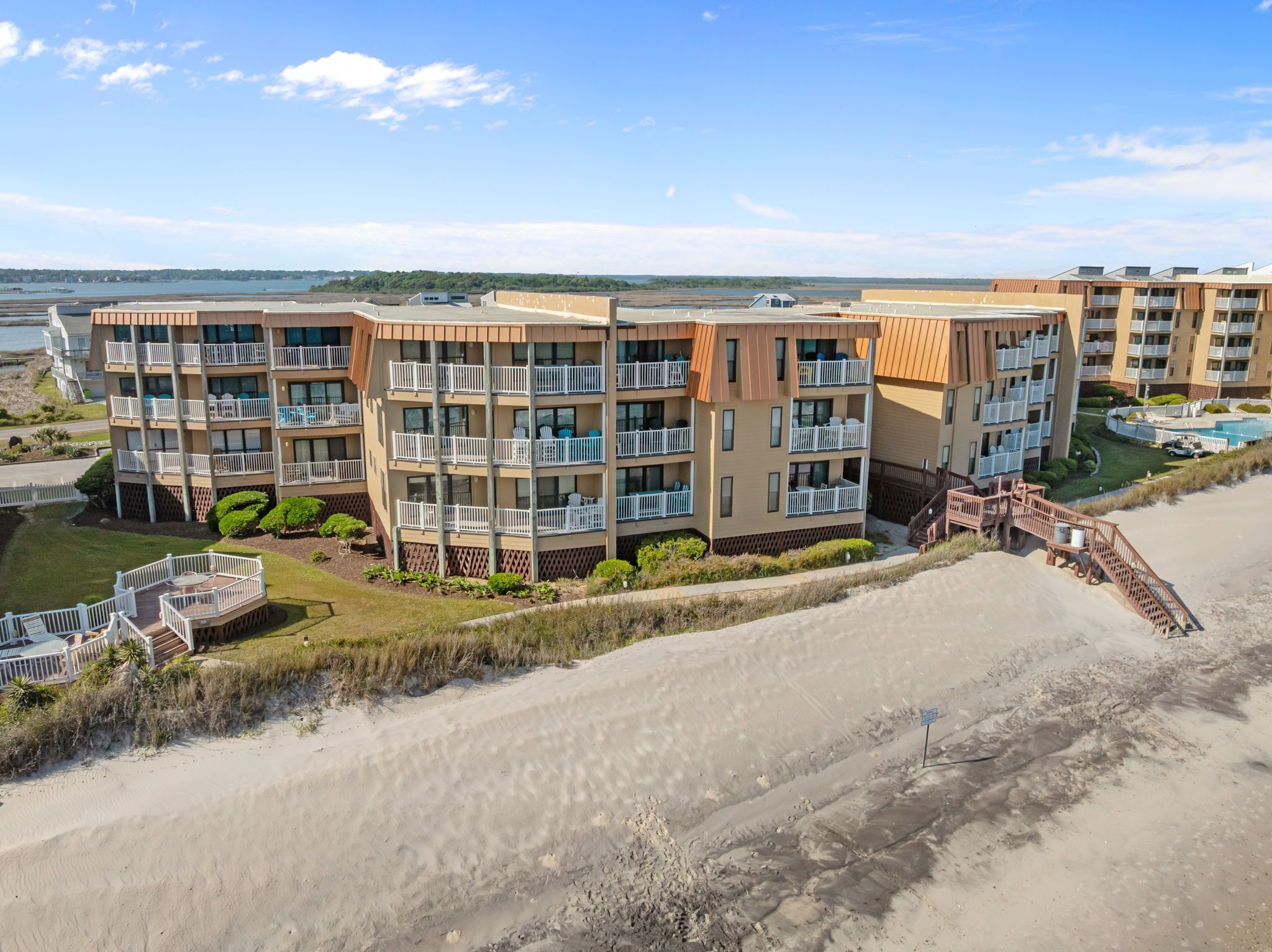 A beachfront hotel with multiple balconies, a pool, and a sandy beach.