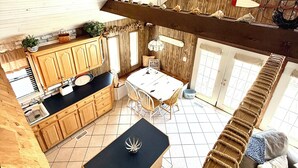 Cuina d'estil loft amb zona de menjador, sostre de fusta i vista a l'exterior.