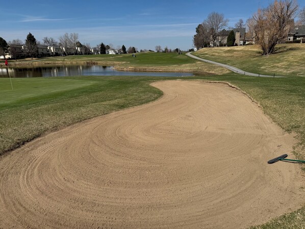 A golf course with a sand bunker, a pond, and a pathway. - Modern 3BR Townhome w/AC, 25 Min to DIA, 30 min to Downtown (Aurora)