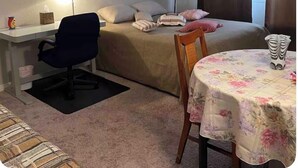 Ein Hotelzimmer mit Bett, Schreibtisch, Stuhl, Tisch, Lampe und einem Bild an der Wand.
