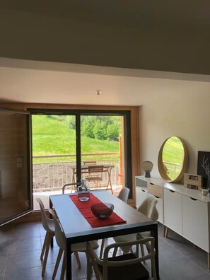 A dining area with a table, chairs, and a view of a balcony with outdoor furniture. - ⛰️ Spacious, comfortable apartment at the foot of the Ancelle slopes - Alps (Ancelle)