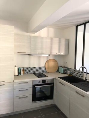 A modern kitchen with white cabinets, a built-in oven, a sink, and a window. - ⛰️ Spacious, comfortable apartment at the foot of the Ancelle slopes - Alps (Ancelle)