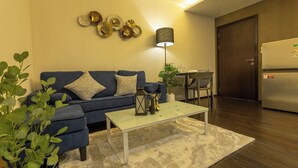 A living room with a sofa, coffee table, lamp, and decorative wall art. - Beach Walk Condo Poolside Retreat by the Sea C123 (Tambon Rawai)