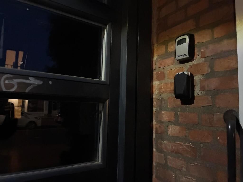 Una puerta con ventanal, un muro de ladrillo y un dispositivo fijado a la pared con la etiqueta 'Master'.