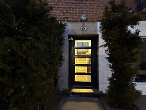 Ein Gebäudeeingang mit einer schwarzen Tür, der Hausnummer 14 und einem kleinen Fenster darüber.