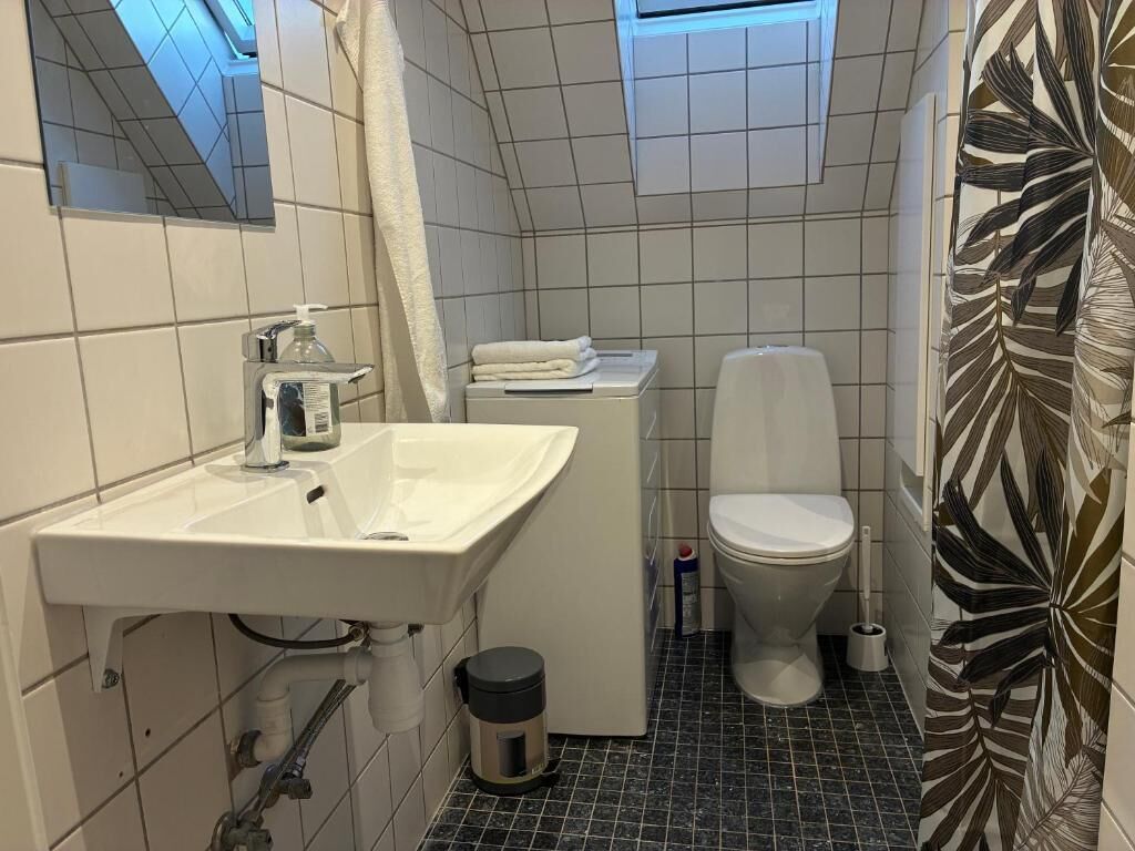 A bathroom with a sink, toilet, and shower curtain.