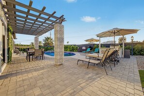 Ein überdachter Patio-Bereich mit Pool, Sitzgelegenheiten im Freien und einer Pergola.