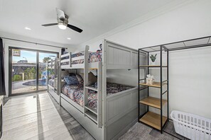 Habitació amb literes, ventilador de sostre, finestra amb vistes i cistella de roba.