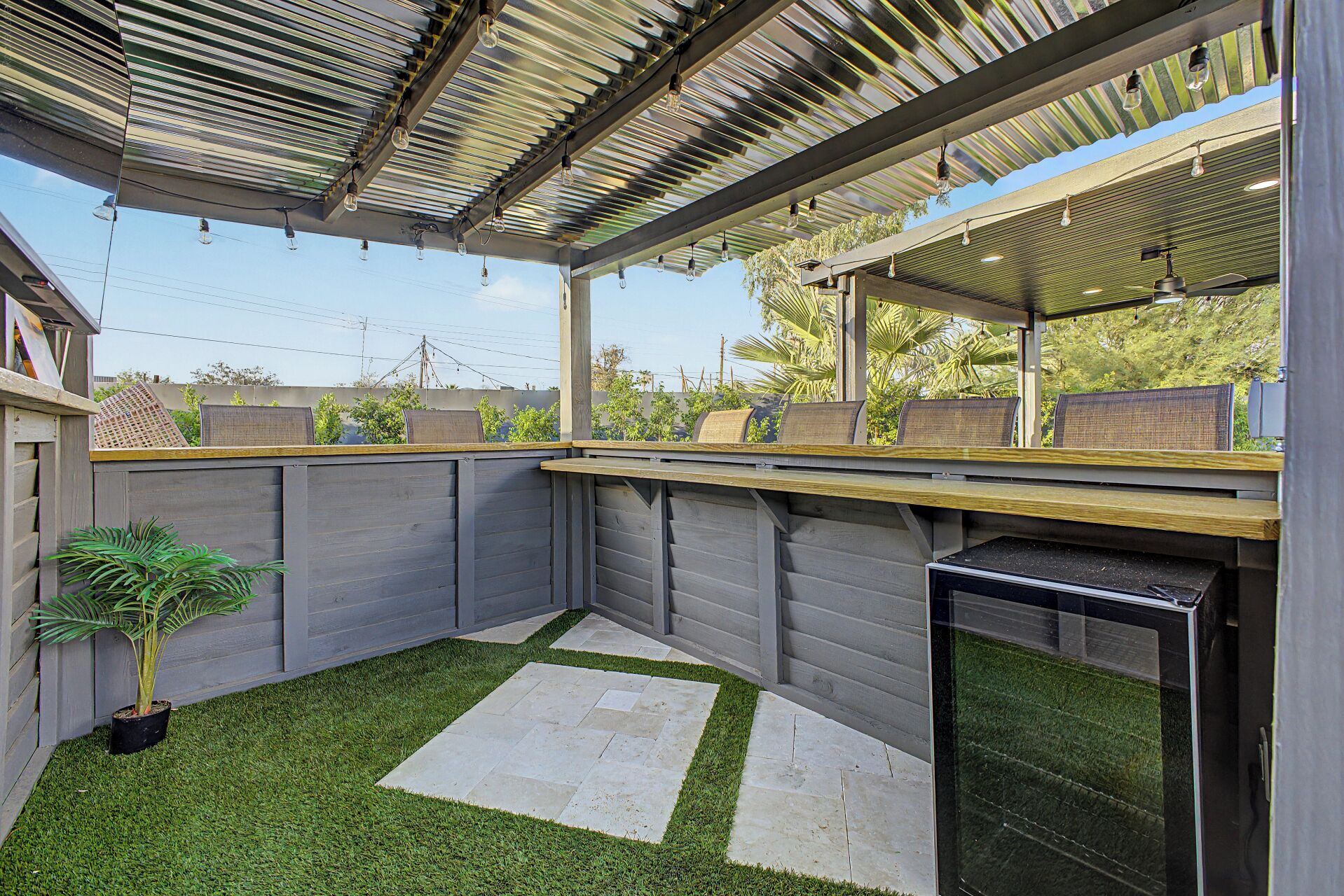 A covered outdoor area with a seating arrangement and a grill.