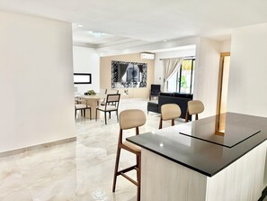 A modern living room with a dining area, a black sofa, and a TV.