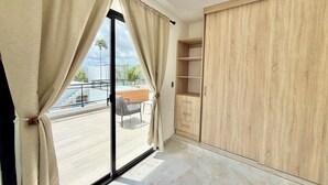 Habitación con puerta de cristal corredera, armario de madera y vistas a una piscina y zona exterior.